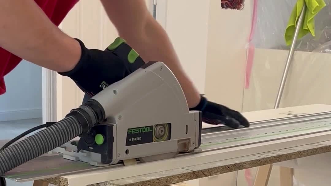 A joiner cutting a board with a Festool track saw on a guide rail.