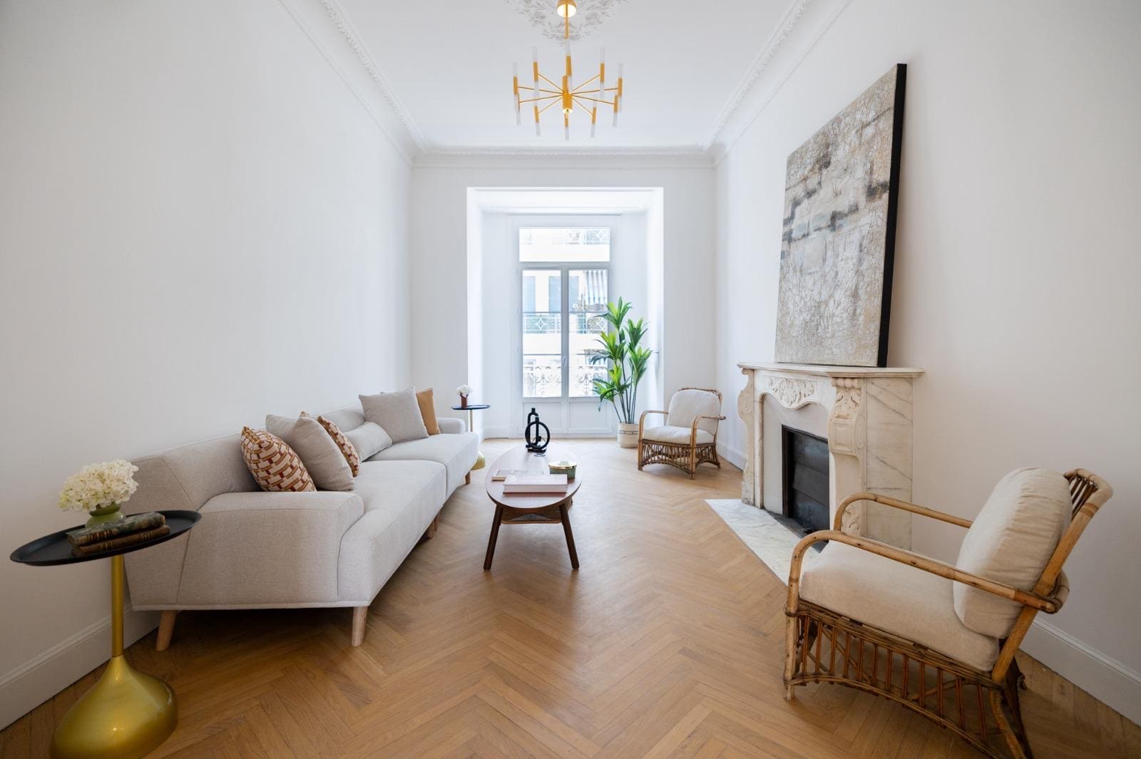 Living room with a light sofa, a marble fireplace and herringbone parquet.